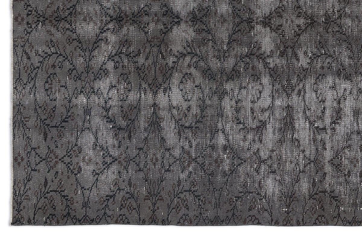 Charcoal and grey distressed rug with a repeating floral medallion pattern.