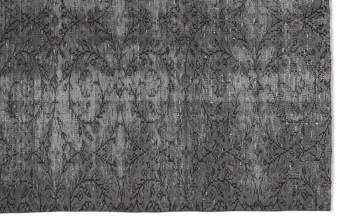 Charcoal grey distressed rug with a faded, repeating floral medallion pattern.