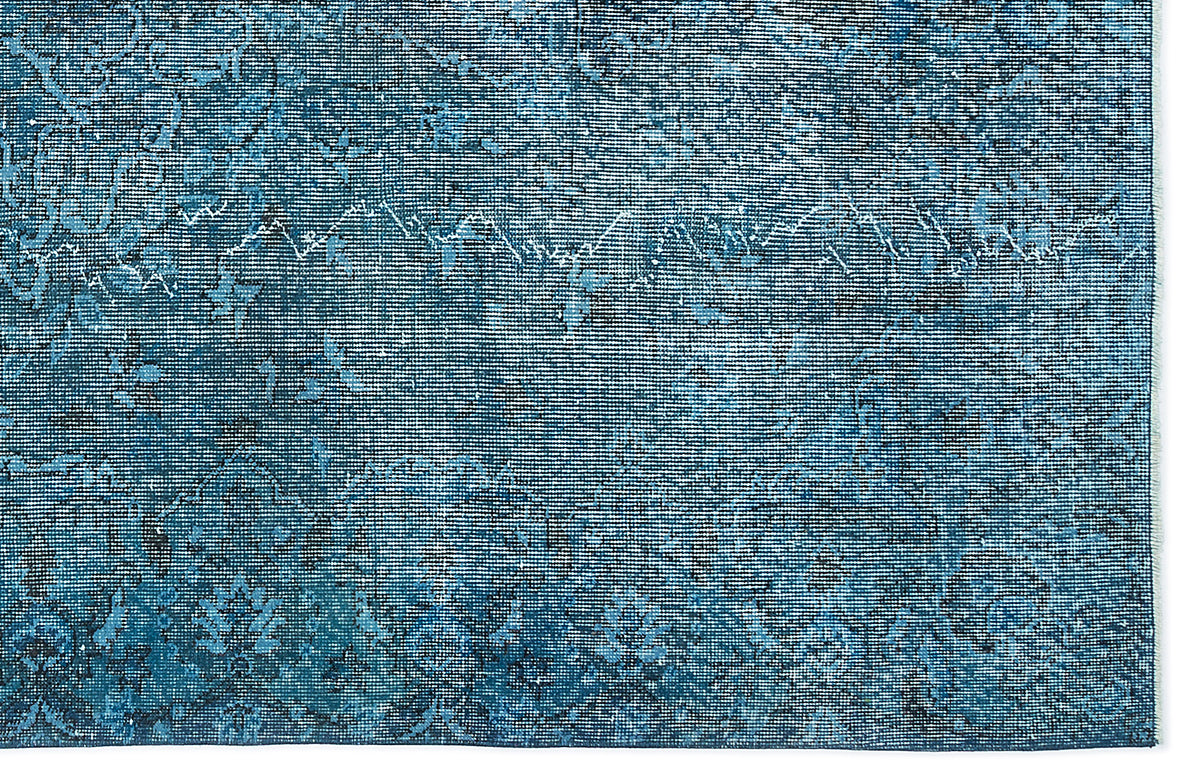 Deep blue distressed rug with a faded traditional floral medallion pattern and visible woven texture.