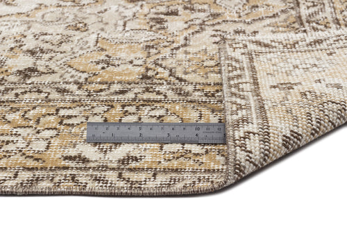 Load image 1 in gallery view. Tan and brown distressed medallion rug with a folded corner and a metal ruler for scale on a white background.