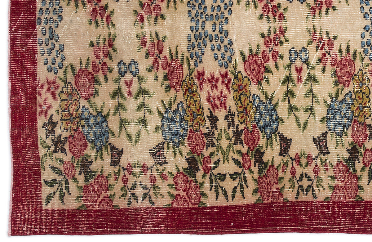 Beige rug with a distressed floral pattern in red, blue, and yellow, featuring a solid red border.
