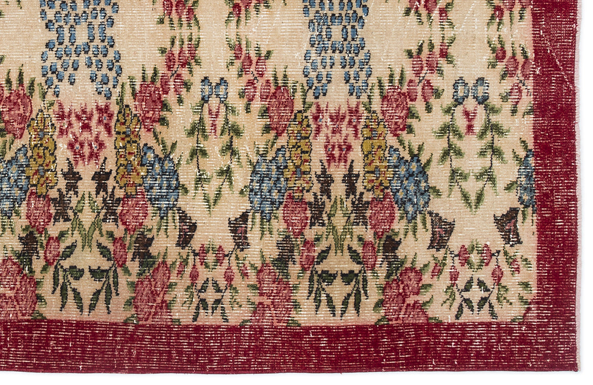 Beige rug with a floral pattern in red, blue, and green, featuring a wide red border.