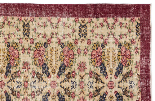 Load image 1 in gallery view. Beige rug with a distressed floral pattern in red, yellow, and navy, featuring a wide solid dark red border.