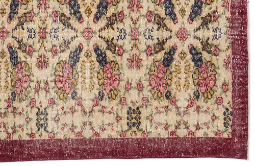 Load image 1 in gallery view. Beige rug with a distressed floral medallion pattern in pink, navy, and mustard, featuring a solid dark red border.