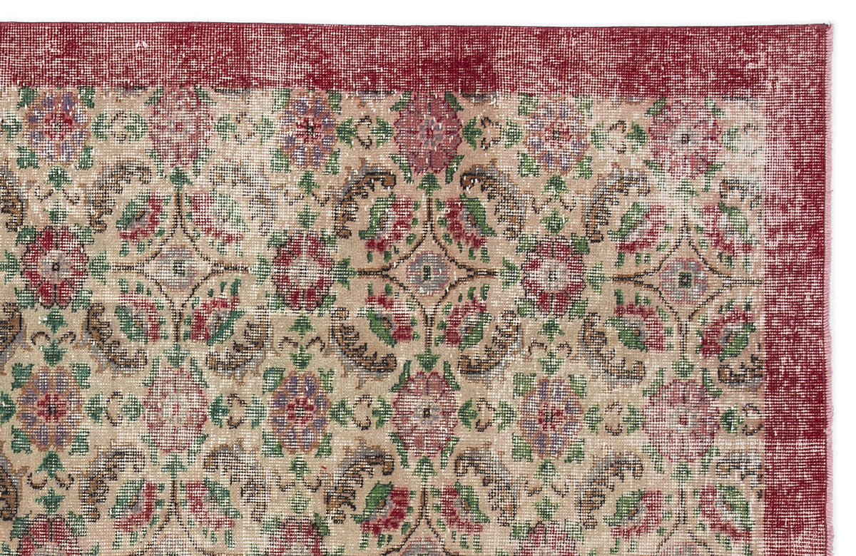 Distressed beige rug with a red border and a repeating floral medallion pattern in red, green, and purple.