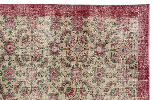Load image 1 in gallery view. Distressed beige rug with a red border and a repeating floral medallion pattern in red, green, and purple.
