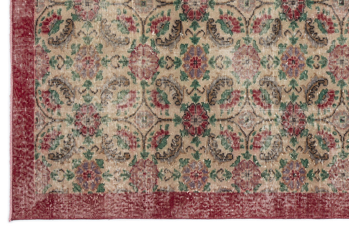 Beige rug with a distressed floral medallion pattern in red, green, and purple, featuring a solid red border.