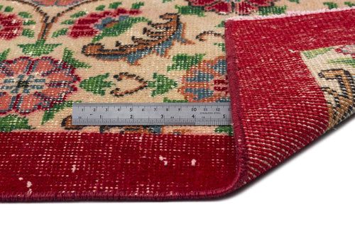 Load image 1 in gallery view. Beige rug with red, green, and blue floral pattern and a wide red border, shown with a metal ruler for scale.