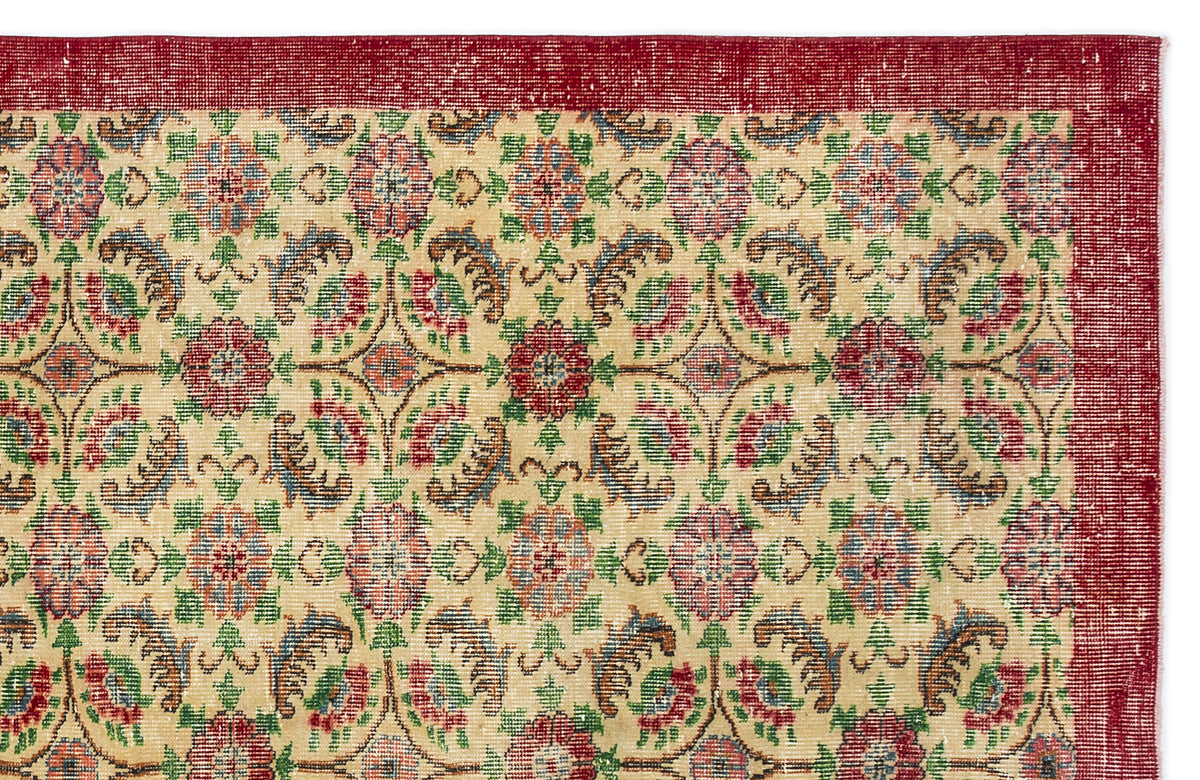 Beige rug with a red border and a repeating floral medallion pattern in red, green, and blue on a white background.