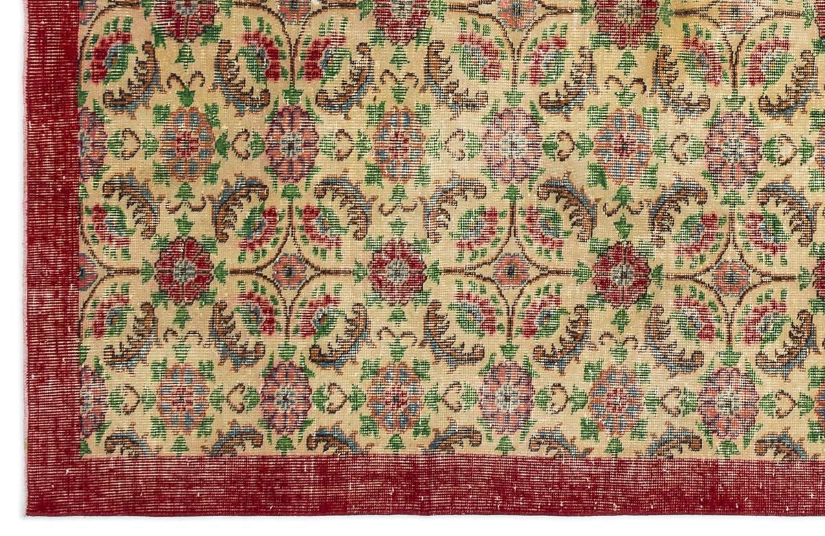 Beige rug with a repeating floral medallion pattern in red, green, and blue, featuring a solid red border.