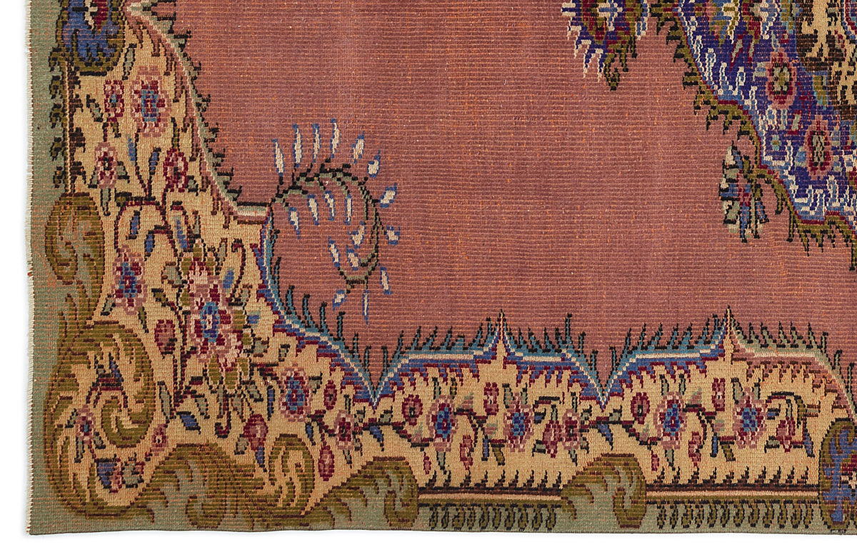 Dusty rose rug with a beige floral border, featuring intricate blue, green, and red traditional Persian-style motifs.