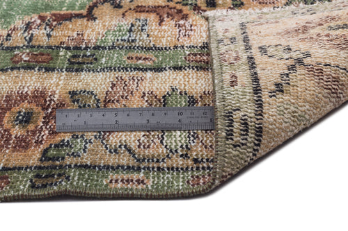 Load image 1 in gallery view. Green, tan, and brown floral patterned rug with a folded corner and a metal ruler for scale on a white background.