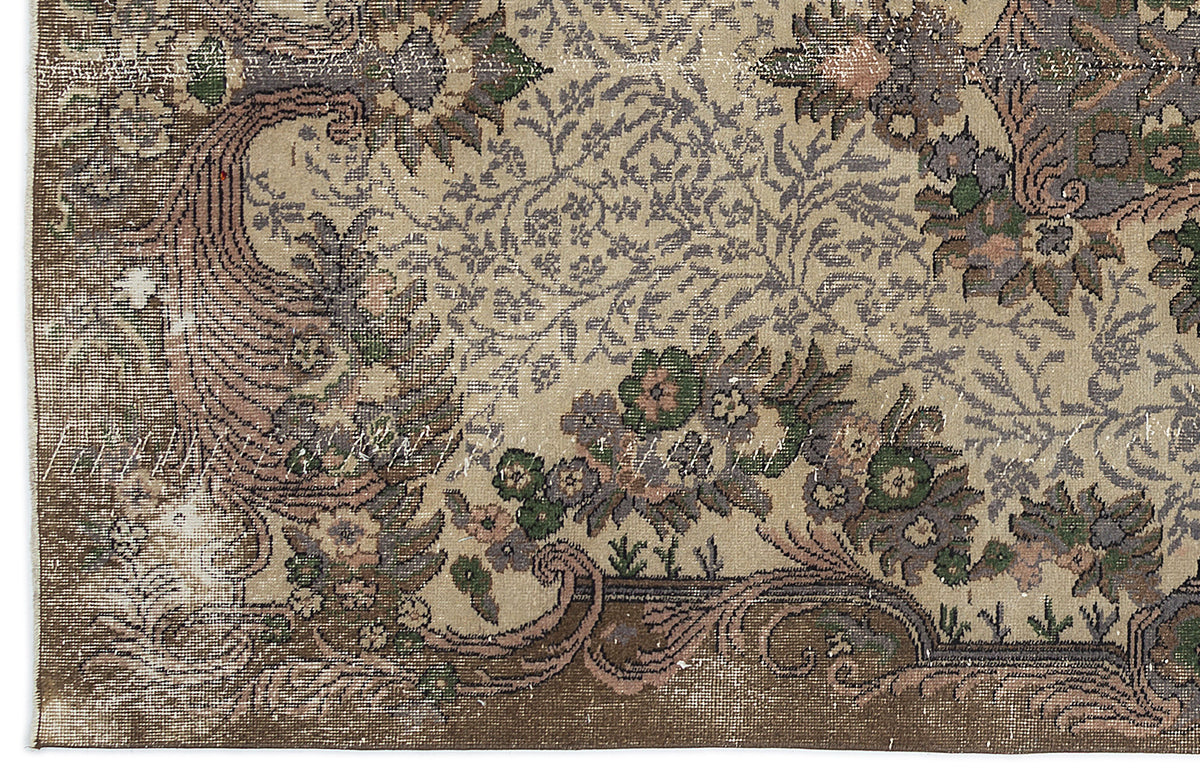 Distressed beige rug with a traditional floral medallion pattern in muted green, brown, and grey tones.