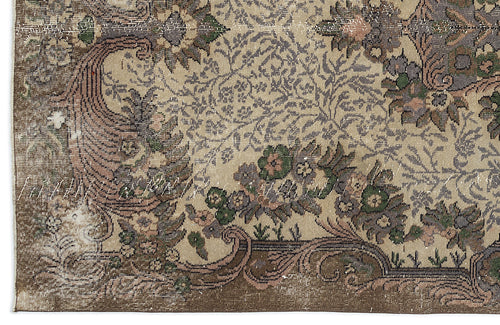 Load image 1 in gallery view. Distressed beige rug with a traditional floral medallion pattern in muted green, brown, and grey tones.