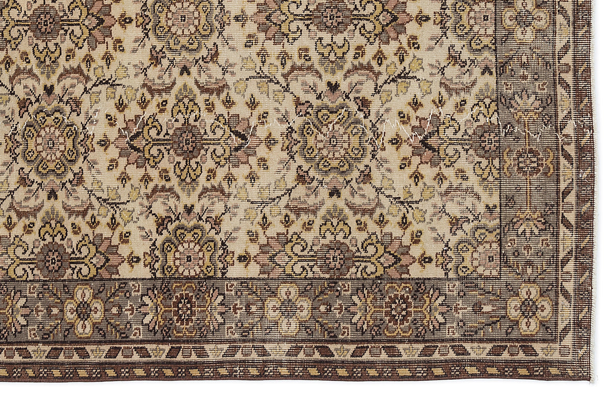 Beige traditional rug with a repeating floral medallion pattern in brown, gold, and muted pink, featuring a wide border.
