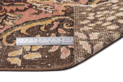 Load image 1 in gallery view. Distressed floral rug in brown, pink, and green with a metal ruler showing pile texture and backing on white background.