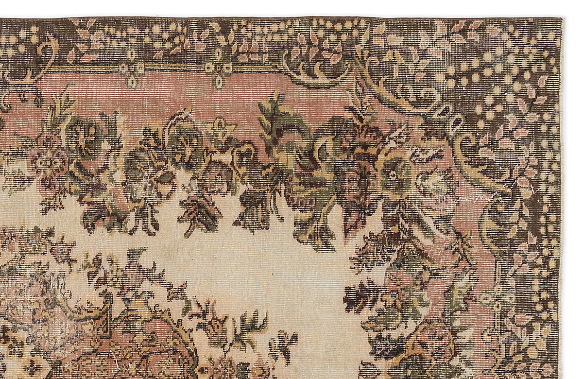 Vintage-style rug corner with a floral medallion pattern in muted brown, sage green, and dusty rose on a cream field.