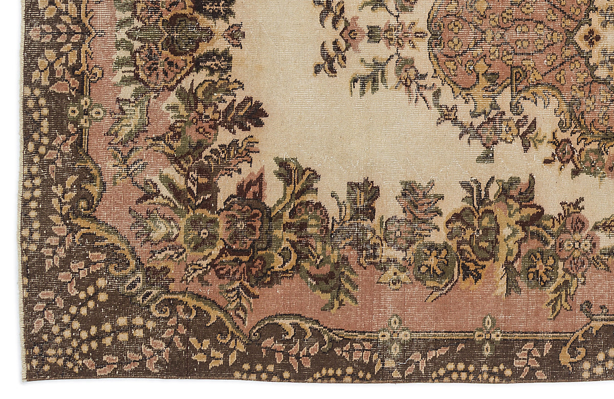 Beige, pink, and dark brown traditional rug with a distressed floral medallion and ornate border pattern.