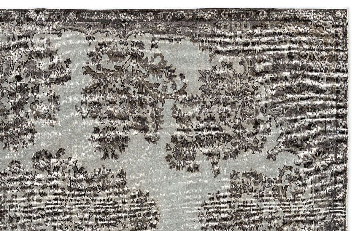 Light gray and charcoal distressed rug with a traditional floral medallion pattern and a dark decorative border.