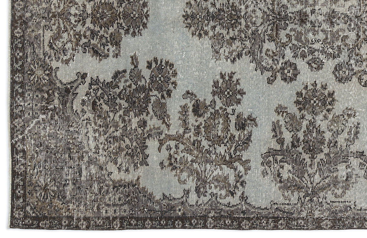 Light blue and charcoal grey rug with a distressed floral medallion pattern and a dark border.