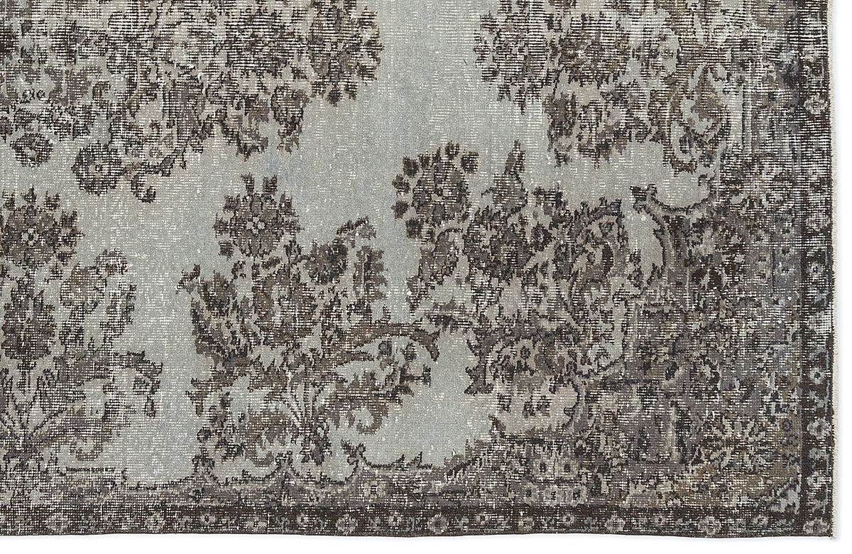 Light blue and charcoal grey rug with a distressed, traditional floral medallion pattern and a dark border.