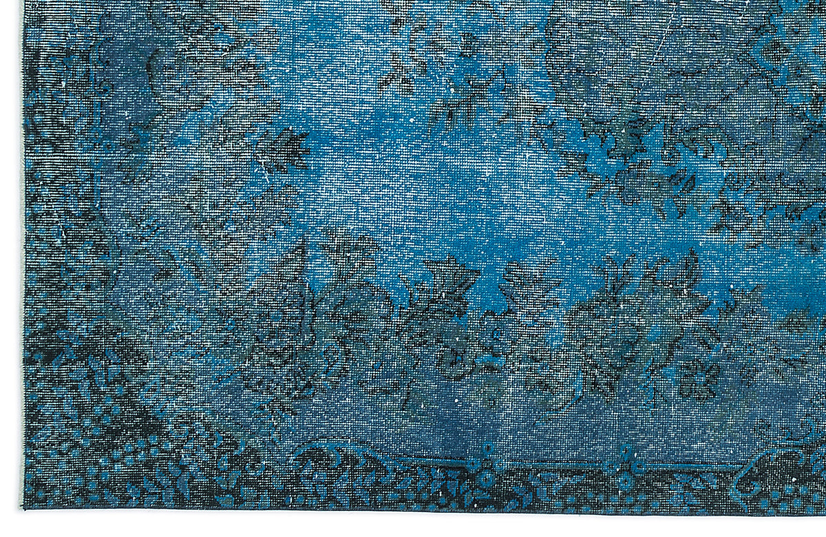 Deep blue distressed rug with a faded black floral medallion pattern and a decorative border.