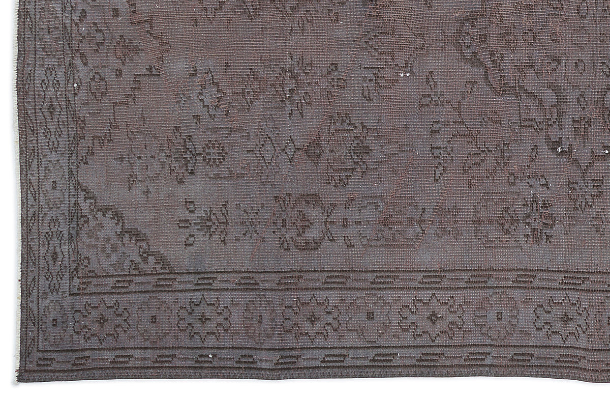 Dark brown vintage-style rug with a faded traditional floral medallion pattern and a geometric border.