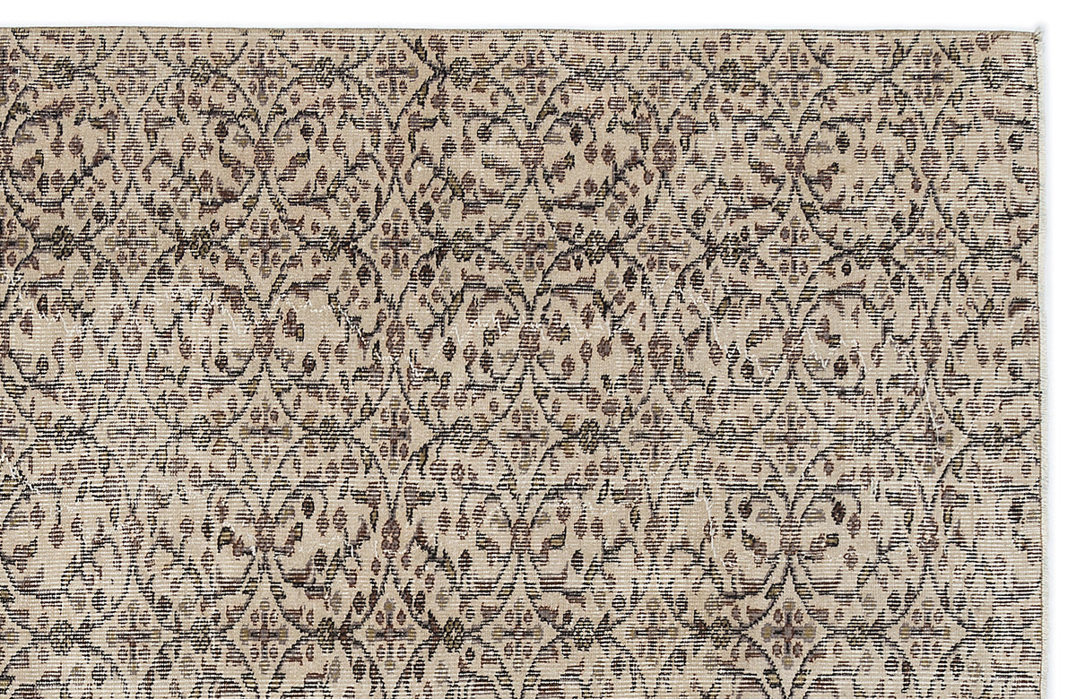 Beige and brown rug with a distressed, repeating lattice and floral medallion pattern.