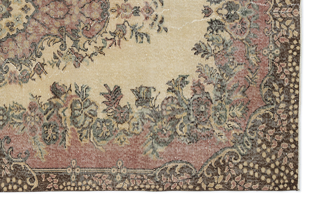Distressed beige rug with a faded floral medallion pattern in muted red, green, and dark brown tones.