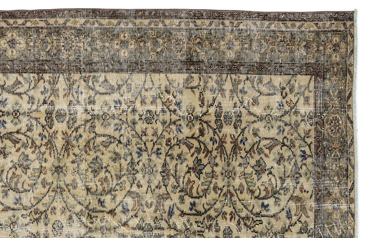 Distressed beige rug with a dark brown border and intricate floral vine pattern in muted blue, green, and brown tones.