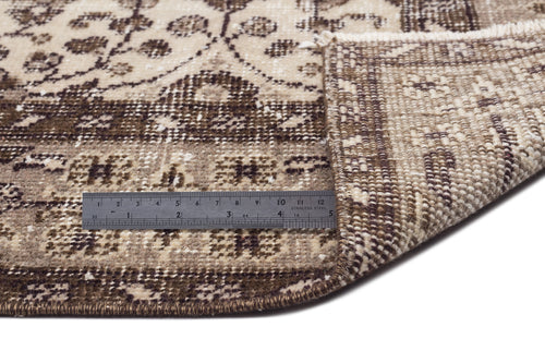 Load image 1 in gallery view. Beige and brown traditional patterned rug with a folded corner and a metal ruler for scale.