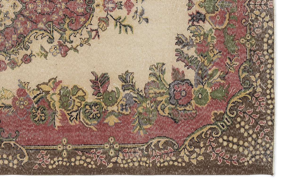 Beige rug with a distressed floral medallion pattern in red, green, and brown with a dark brown border.
