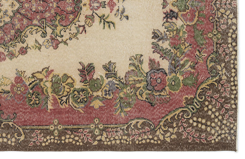 Load image 1 in gallery view. Beige rug with a distressed floral medallion pattern in red, green, and brown with a dark brown border.