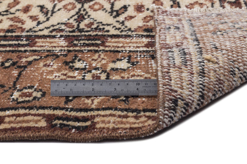 Load image 1 in gallery view. Beige and brown traditional floral rug with a folded corner and a stainless steel ruler for scale.