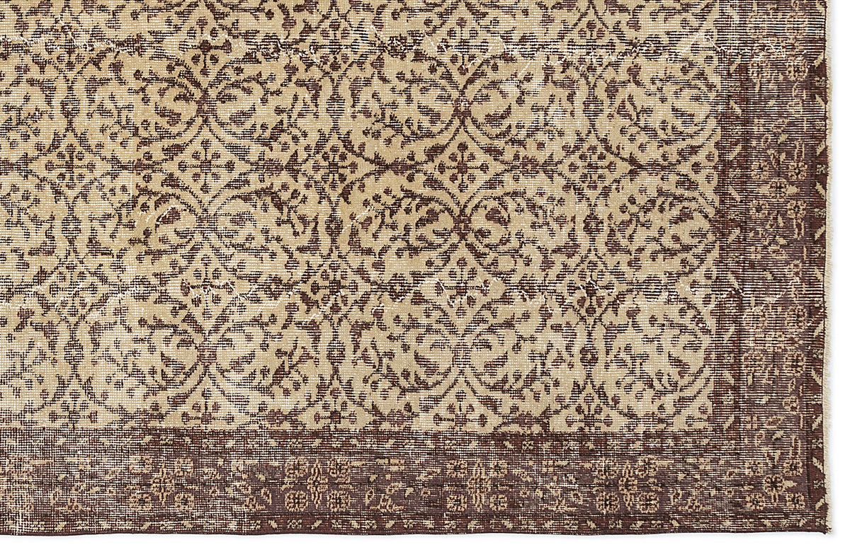 Beige and dark brown rug with a distressed, repeating floral medallion pattern and a wide decorative border.