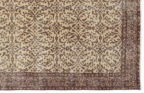 Load image 1 in gallery view. Beige and dark brown rug with a distressed, repeating floral medallion pattern and a wide decorative border.