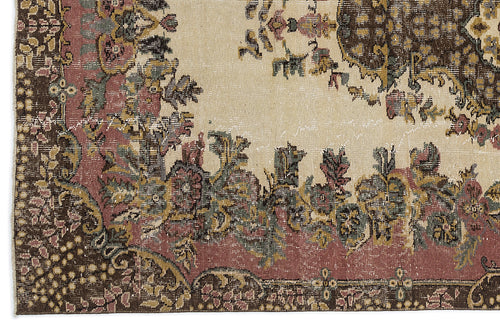 Load image 1 in gallery view. Distressed vintage-style rug with a cream field, dark brown borders, and floral medallion motifs in muted pink and green.