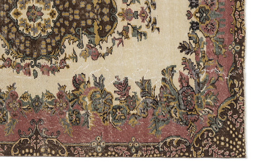 Load image 1 in gallery view. Distressed traditional rug with a cream field, dark brown medallion, and floral border in muted pink, green, and gold.