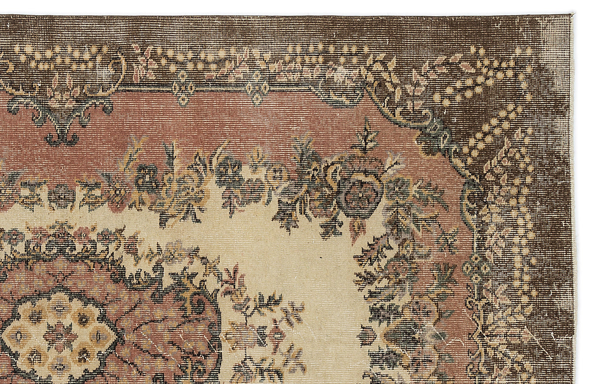 Traditional rug corner with a dark brown border, dusty rose field, and cream center featuring floral medallion motifs.