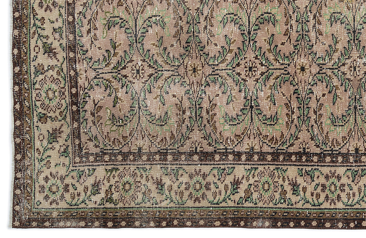 Distressed taupe and green rug with a traditional floral vine pattern and a dark brown geometric border.