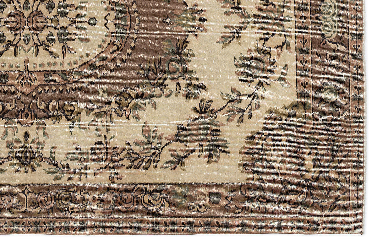 Distressed beige rug with a brown floral medallion and vine border pattern on a white background.