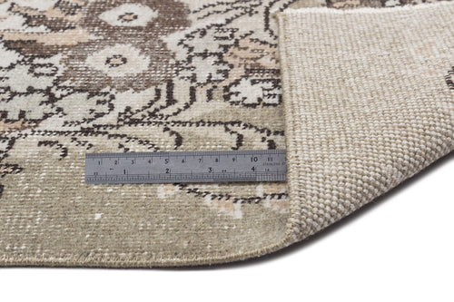 Load image 1 in gallery view. Beige and brown distressed floral rug with a metal ruler showing pile thickness on a white background.