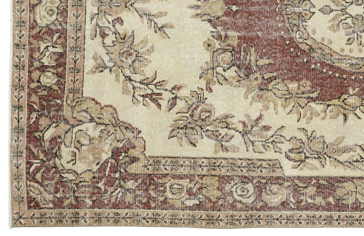 Distressed cream and terracotta rug with a floral medallion pattern and a decorative border.