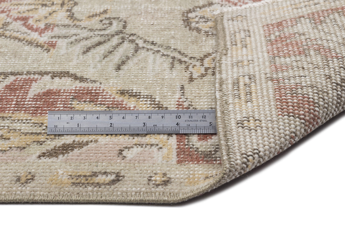 Beige, brown, and muted red vintage-style rug with a floral pattern, shown with a metal ruler for scale.
