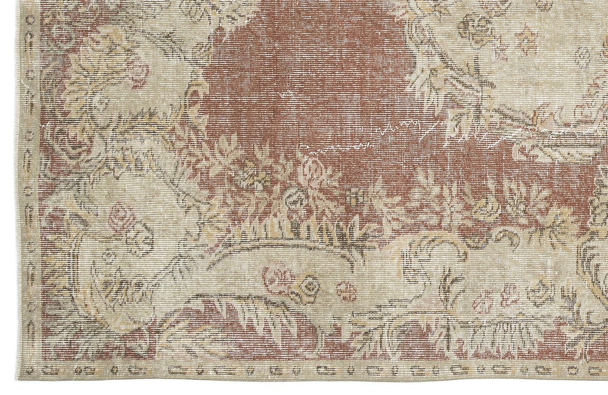 Distressed terracotta and beige rug with a traditional floral medallion pattern and a woven border.