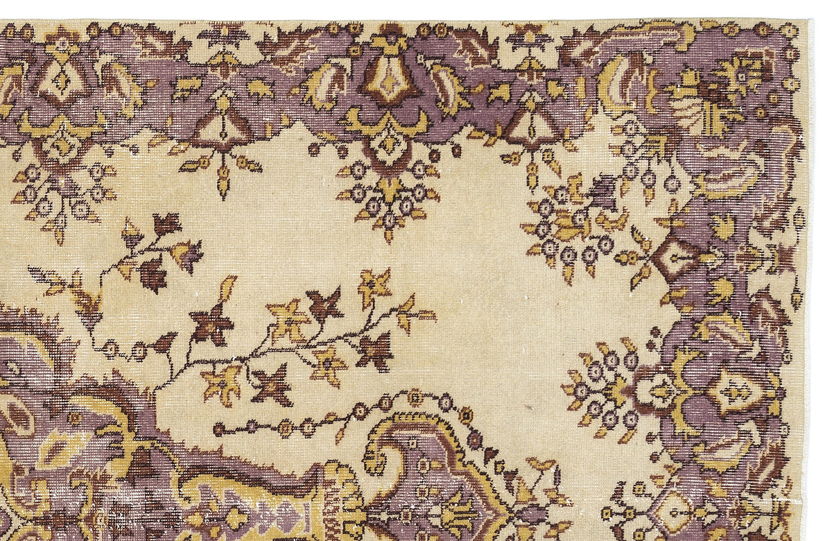 Beige rug with a purple and gold floral border and scattered botanical motifs.