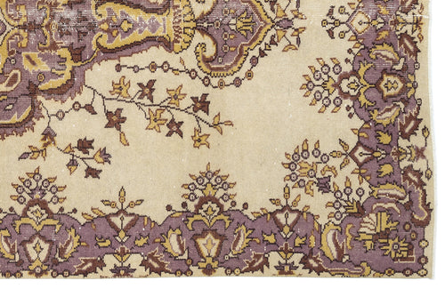 Load image 1 in gallery view. Beige rug with a distressed floral and paisley pattern in muted purple, brown, and mustard yellow.