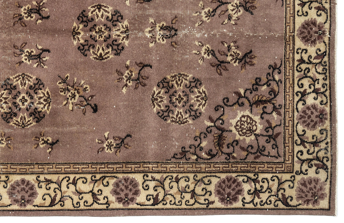 Mauve rug with dark brown circular medallions, floral motifs, and a cream-colored border with a geometric Greek key pattern.