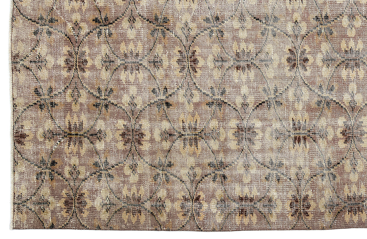 Taupe and beige rug with a distressed trellis pattern featuring repeating floral medallions.