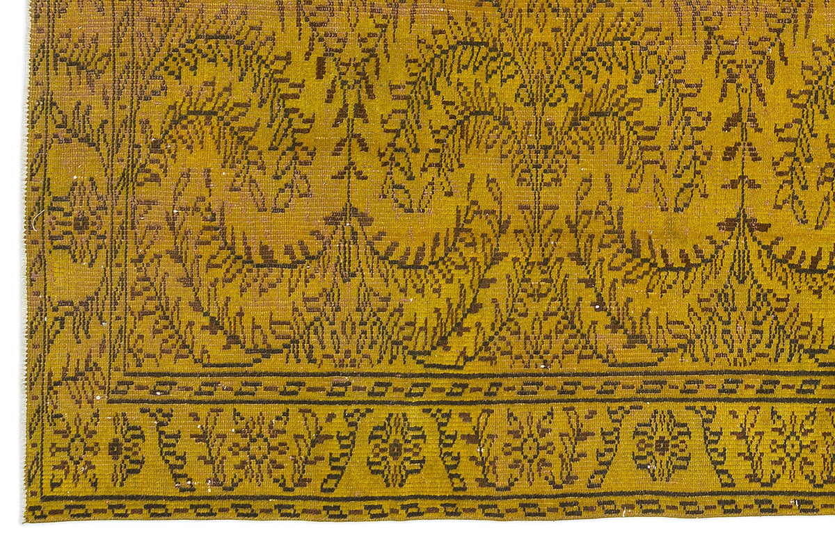 Mustard yellow rug with a dark brown botanical vine pattern and a geometric border.